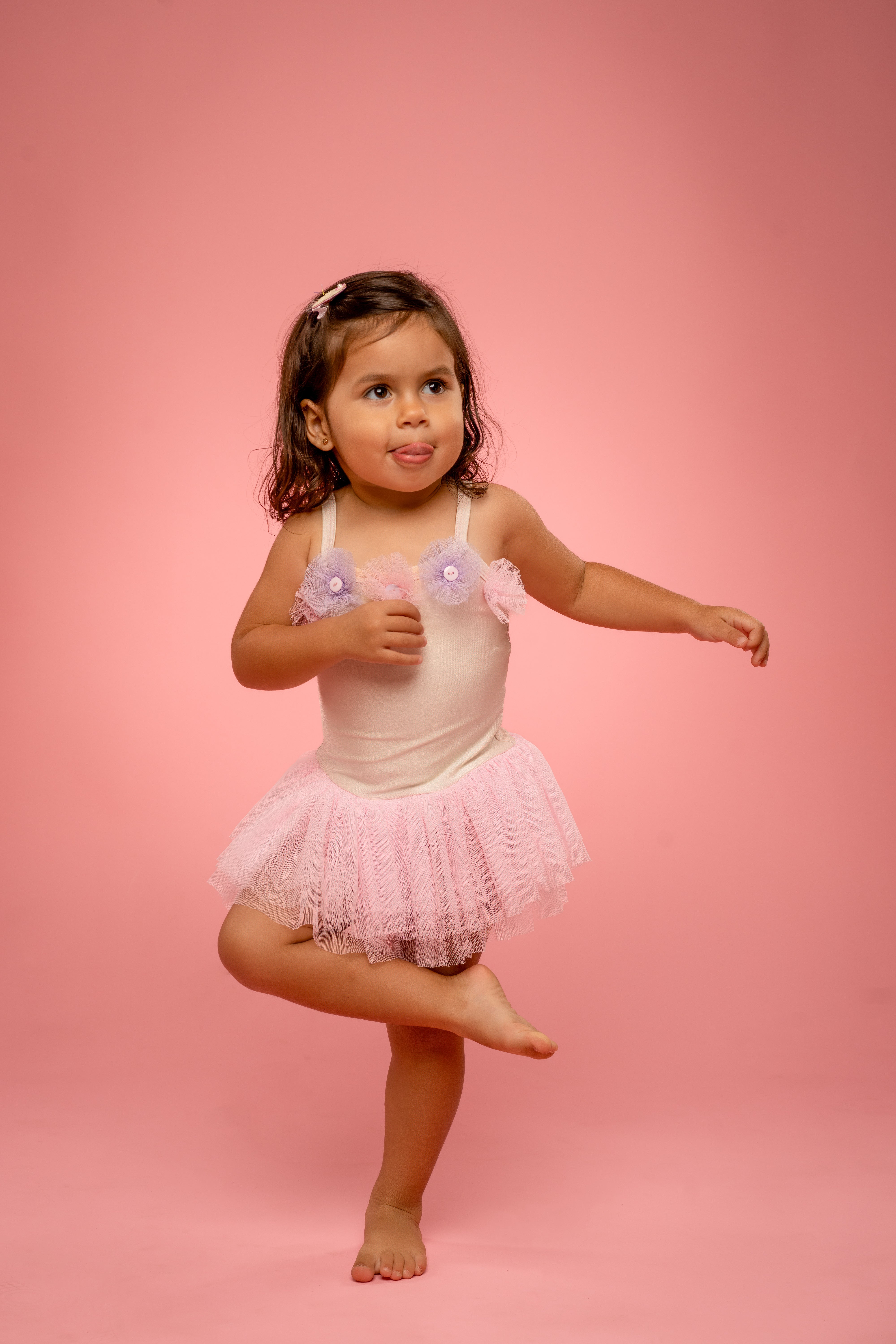 Young girl in a pink ballet outfit posing on a pink background in a studio portrait session in the cayman islands