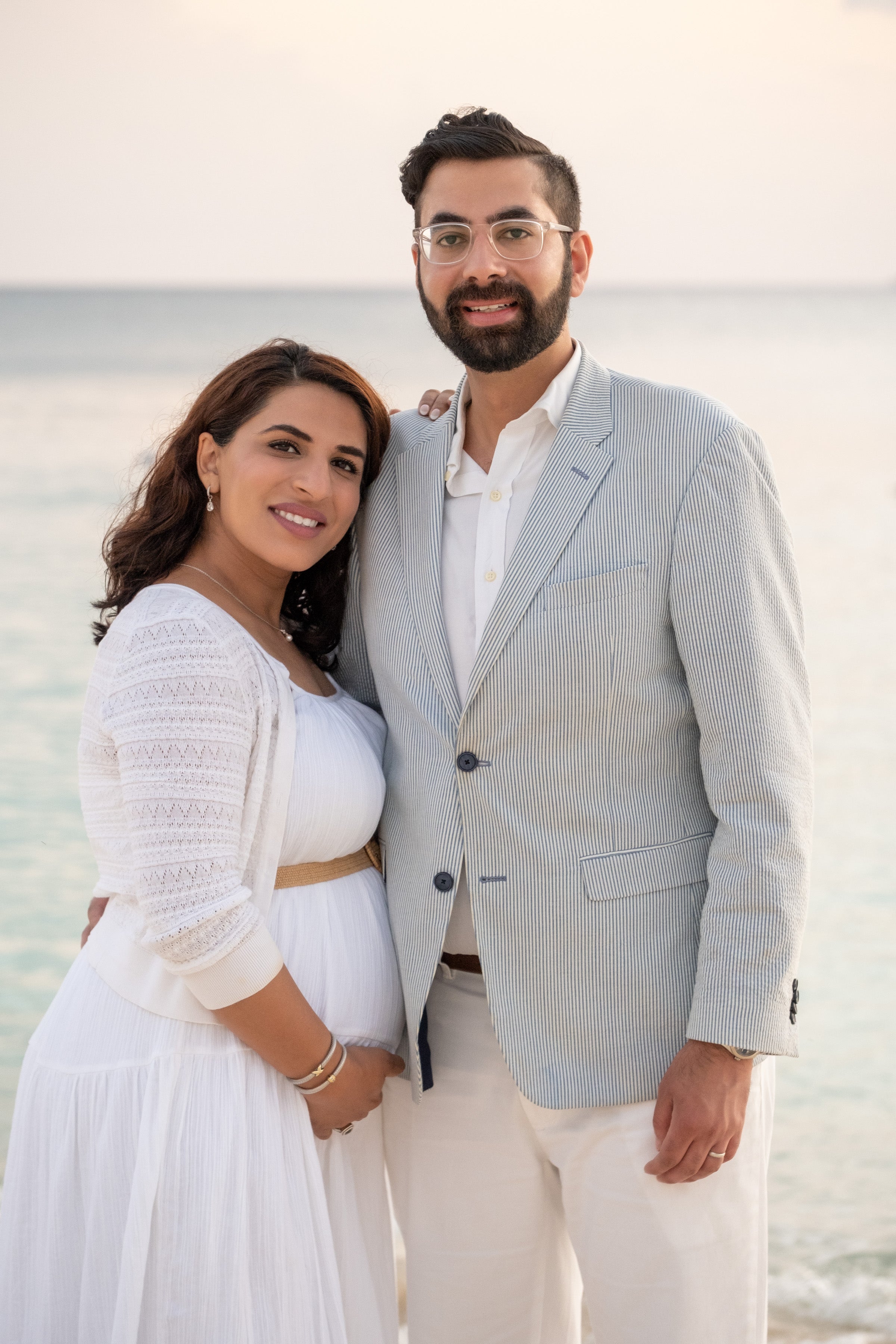 Man and woman standing close together on a beach with a blurred background. Cayman Islands couples babymoon photography