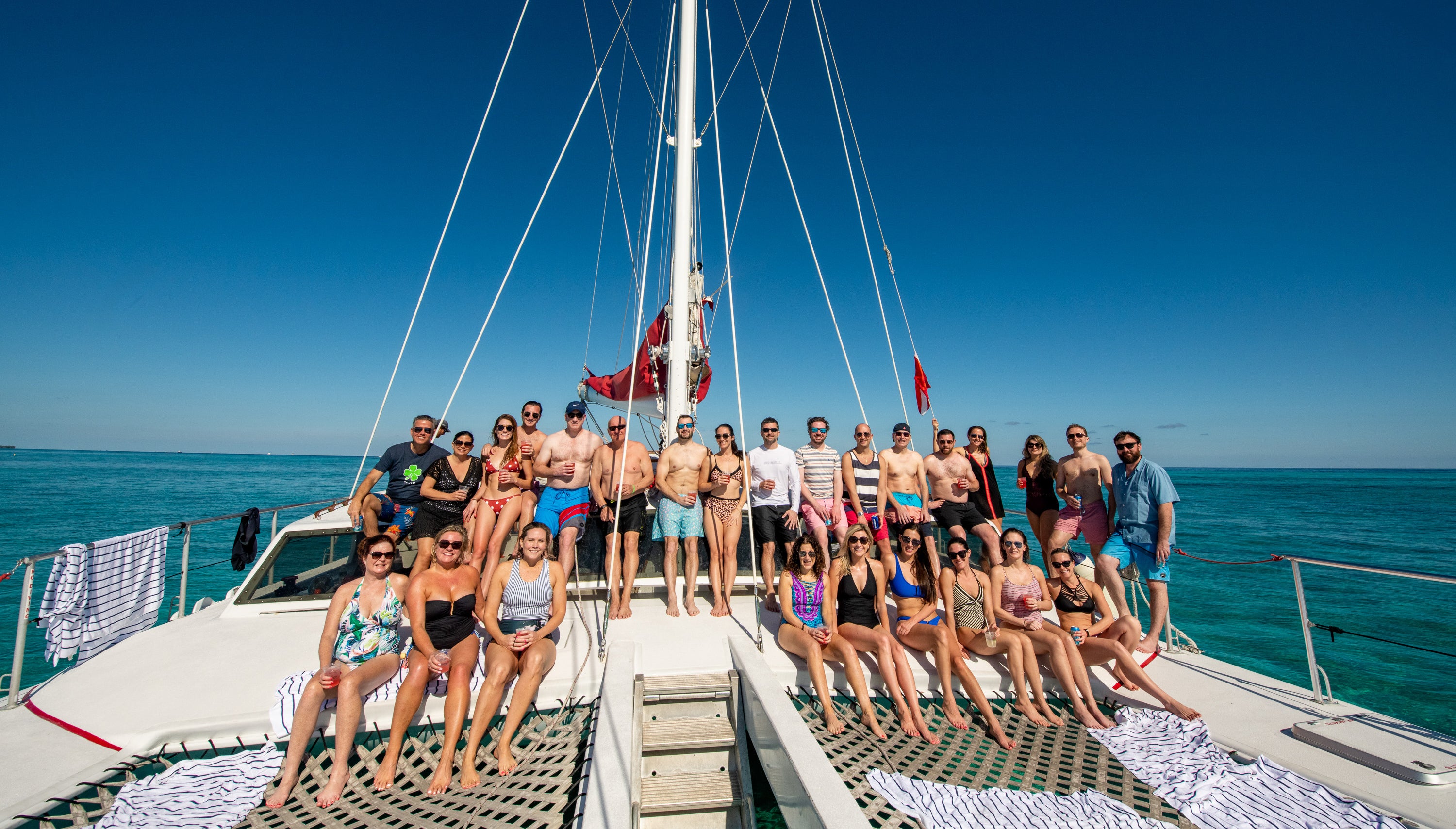 Group of people on a catamaran in the ocean with clear blue sky. Corporate and incentive photography Cayman Islands