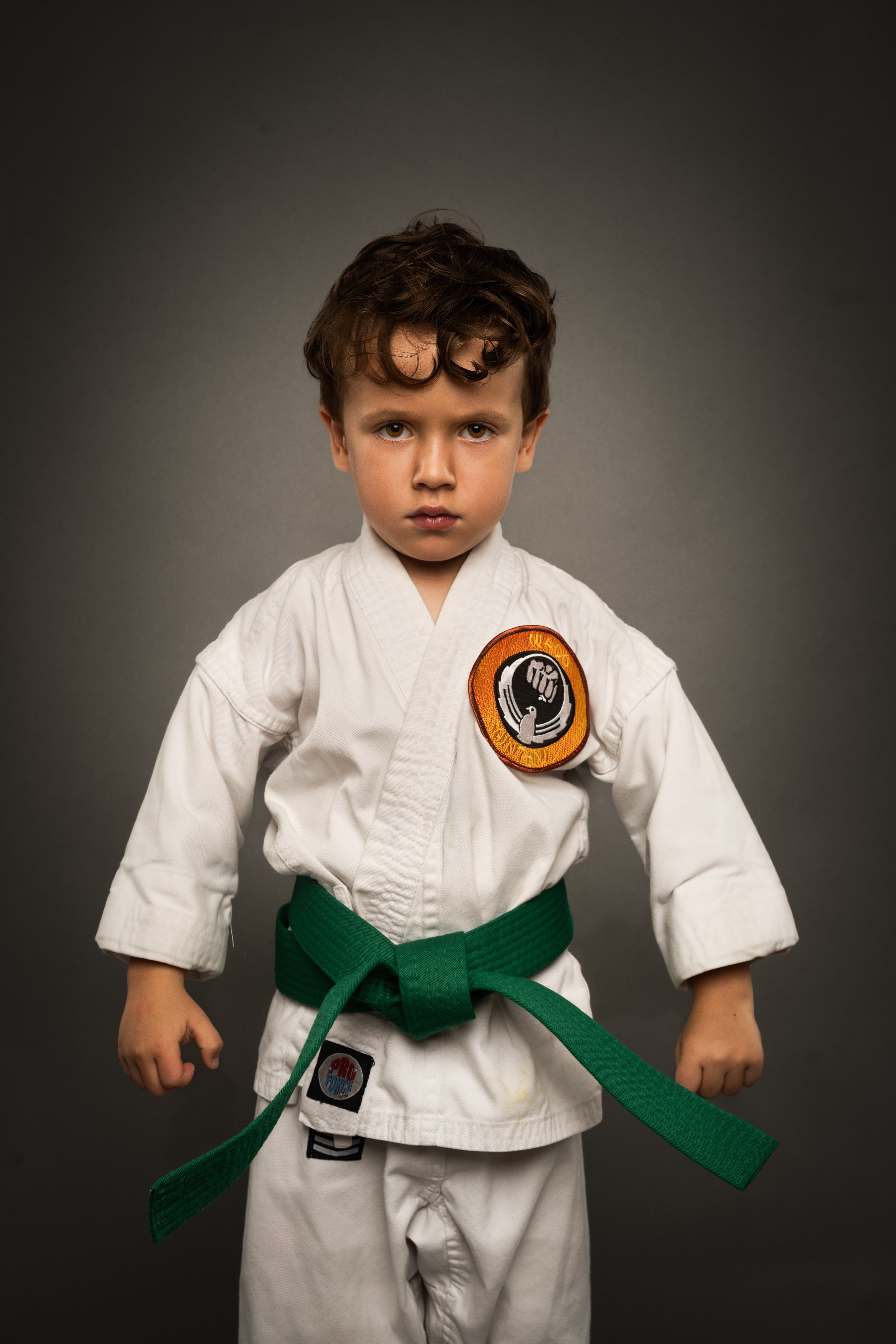 Child in a white martial arts uniform in a cayman islands kids sports studio portrait session.