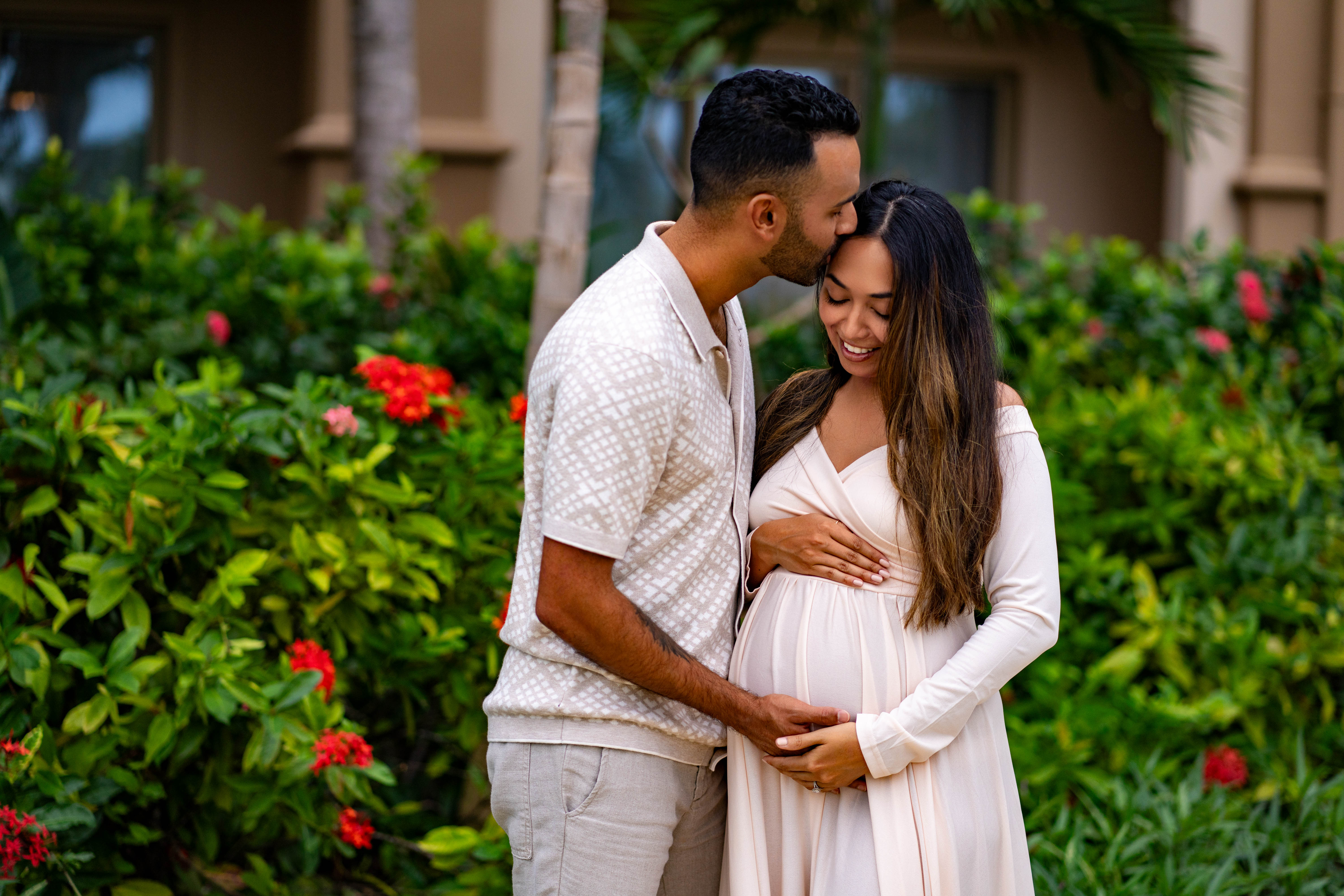 Man and woman standing close together in a garden with greenery and flowers.
