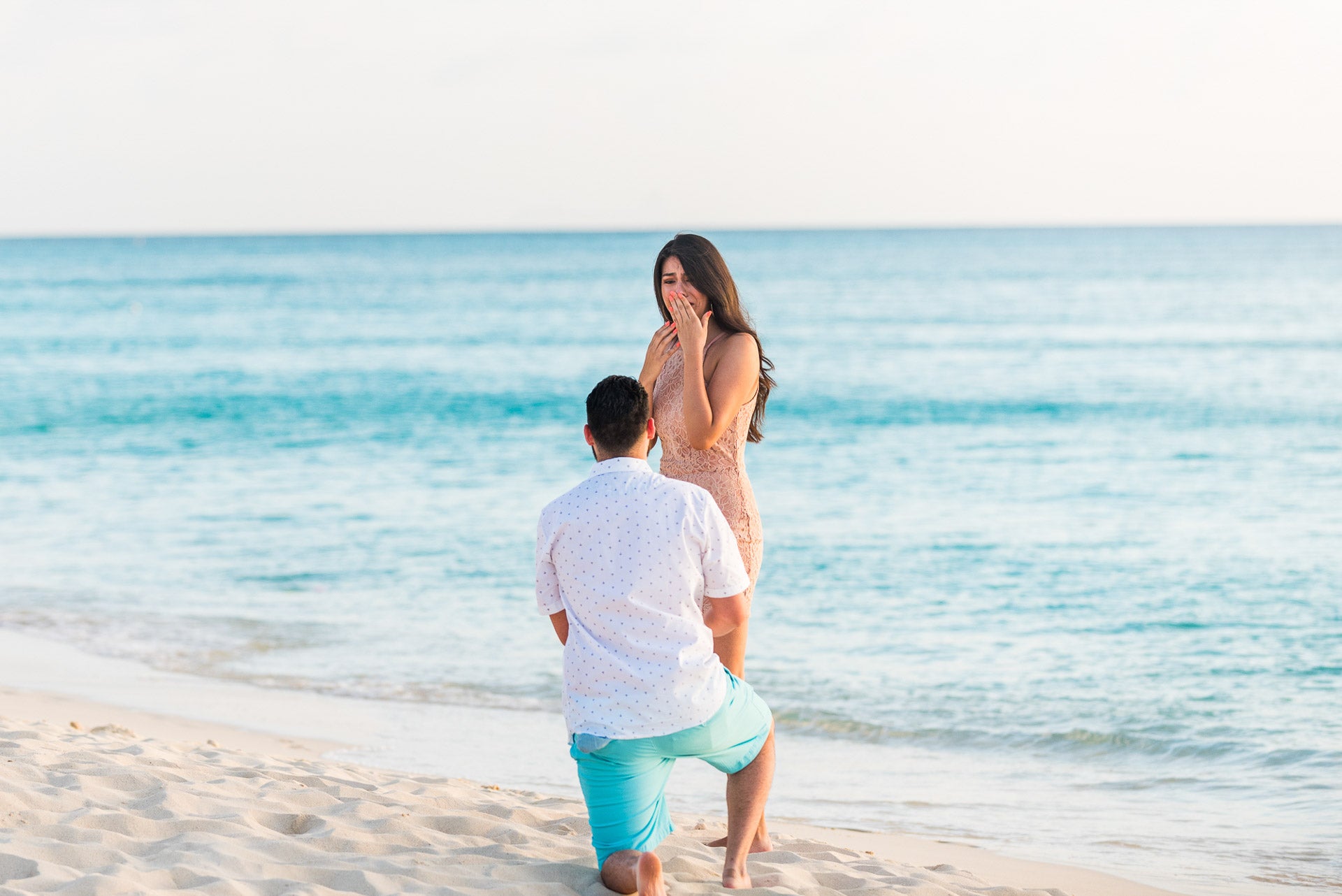 Man proposing to a woman on a beach with ocean in the background, engagement photography ritz-carlton grand cayman